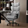 A gray ergonomic office chair is shown in a modern office or home office setting, with a bookshelf and desk in the background. Náhled obrázku produktu