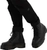 A close-up shot of a person wearing black pants and black Dr. Martens boots. Anteprima dell’immagine prodotto
