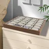 A watch organizer box with multiple compartments sits on top of a dresser. Two watches are visible inside the organizer. Podgląd zdjęcia produktu
