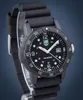 A black Luminox watch with a black rubber strap is displayed on a stand against a dark blue and gray gradient background. Produktbild-Vorschau