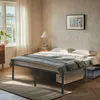 A bedroom scene with a bed frame and bedding, a nightstand with a lamp, and a window with curtains. Produktbild-Vorschau
