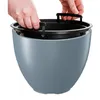 Hands are shown inserting a black plastic planter insert into a larger gray planter pot. Produktbild-Vorschau