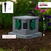 A gray, stone-look outdoor electrical outlet box is shown in a garden setting. Produktbild-Vorschau