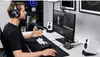 A man is sitting at a desk with a computer setup, wearing headphones and speaking into a microphone. Produktbild-Vorschau