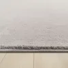 A close-up view of the edge of a light gray carpet on a light wooden floor. Produktbild-Vorschau