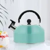 A teal whistling kettle on a marbled surface with a glass of fruit parfait in the foreground and a plant leaf in the background. Podgląd zdjęcia produktu
