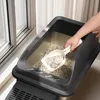 A person is scooping waste from a cat litter box with a scoop. Produktbild-Vorschau