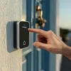 A hand is pressing a doorbell button on a wall next to a blue door. Náhľad obrázku produktu