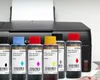 Bottles of printer ink in front of a Canon printer. Produktbild-Vorschau