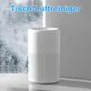 A white air purifier sits on a reflective surface in front of a blurred background of snowy trees. Produktbild-Vorschau