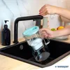A person is filling a water filter pitcher under a faucet in a kitchen sink. Náhled obrázku produktu