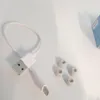 A white USB-C charging cable and several gray ear tips are laid out on a white surface. Produktbild-Vorschau