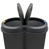 Close-up view of the top of a black dual-compartment trash bin with both lids open. Voir les images du produit