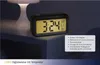 A digital alarm clock is displayed on a nightstand next to a lamp. Náhled obrázku produktu