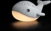 A white whale-shaped night light is shown against a black background. Produktbild-Vorschau