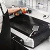 A person is spraying a griddle with cooking spray. Produktbild-Vorschau