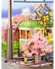 A close-up of a wooden model train station with cherry blossom trees. Produktbild-Vorschau