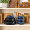 Kitchenware items including plates, bowls, and utensils are neatly arranged on wooden shelves. Produktbild-Vorschau