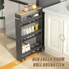 A narrow shelving unit with wheels is placed between a refrigerator and kitchen cabinets, filled with various jars and containers. Produktbild-Vorschau