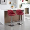 Two red bar stools are placed in front of a kitchen island with a white countertop and wooden cabinets. In the background, there is a white fireplace decorated for Christmas. Produktbild-Vorschau