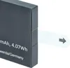 A close-up of a black battery pack with a white pull tab and an arrow pointing to the right. Produktbild-Vorschau