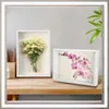 Two shadow boxes with floral arrangements on a wooden desk. Anteprima dell’immagine prodotto