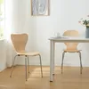 Two wooden chairs are placed around a white table in a well-lit room. Voir les images du produit