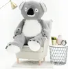 A large plush koala bear sits in a chair next to a small table with decorative items. Anteprima dell’immagine prodotto