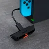 A close-up shot of a black Bluetooth audio adapter connected to a blue Nintendo Switch controller and dock. Podgląd zdjęcia produktu