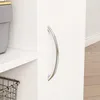 A close-up view of a white cabinet door with a silver handle, next to a shelf with a grey bin and a wire basket. Produktbild-Vorschau
