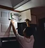 A person is reaching into a kitchen cabinet to retrieve a box of cookware. Náhled obrázku produktu