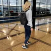 A woman walks through an airport with a backpack. Produktbild-Vorschau
