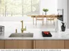 A modern kitchen scene featuring a gold faucet and sink, with a dining area and fireplace in the background. Podgląd zdjęcia produktu