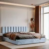 A bedroom scene featuring a light blue upholstered bed with pillows and a throw blanket. Anteprima dell’immagine prodotto