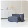 A folded mattress with a pillow is placed on a white floor in front of a white cabinet. Voir les images du produit