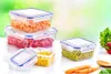 Several clear plastic food storage containers filled with colorful chopped vegetables and peas, arranged on a white surface with a blurred green background. Carrots, a red pepper, and lettuce are also visible. Anteprima dell’immagine prodotto