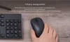 A hand holding a black wireless mouse next to a black keyboard on a wooden surface. Anteprima dell’immagine prodotto