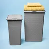 Two gray laundry baskets are shown against a light blue background. One basket is smaller and to the left, while the larger basket is to the right and has two yellow towels stacked on top of its lid. Anteprima dell’immagine prodotto