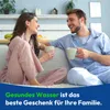 A couple sitting on a couch, drinking from mugs and smiling at each other. Produktbild-Vorschau