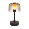 A table lamp with a black base and stem, and a transparent brown shade with a yellow light inside. Anteprima dell’immagine prodotto