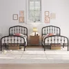 Two black metal twin beds are set up in a bedroom with a window and wall decor. Produktbild-Vorschau