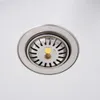 A close-up view of a stainless steel sink drain with a gold stopper. Voir les images du produit