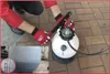 A person wearing red gloves is using a fluid transfer system, with a collection container in the foreground. Náhľad obrázku produktu