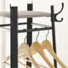 Close-up of a black metal and wood garment rack with several wooden hangers. Produktbild-Vorschau
