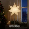 A lit star lamp is placed on a surface next to a Christmas tree and candles, with a window in the background. Podgląd zdjęcia produktu