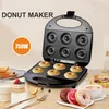 A donut maker with donuts being made inside, along with some finished donuts and breakfast items. Náhled obrázku produktu