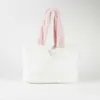 A white fluffy tote bag with pink handles against a white background. Voir les images du produit