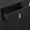 A close-up view of a black dresser with a fluted design and gold handles. One drawer is partially open, revealing the interior. Anteprima dell’immagine prodotto