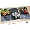 A glass cutting board with a food-themed print is placed on a kitchen countertop, covering a stovetop with a pot on it. Podgląd zdjęcia produktu
