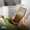 A person is holding a smartphone and interacting with a smart heater. Produktbild-Vorschau